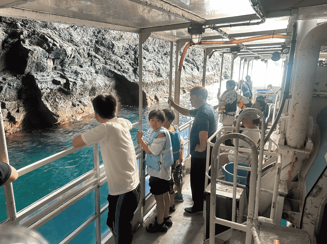 愛南町・西海観光船が所有する船を使って、天然洞窟「鹿島のウド」へ船ごと入って、洞窟内の様子を親子で観察している