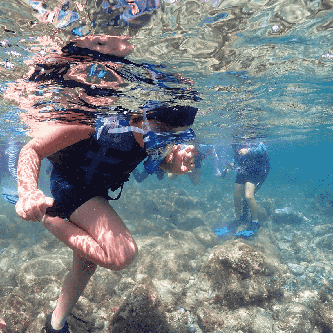 地域の子供が、初めて海の中をシュノーケルで覗いている様子を、水中から撮影した写真